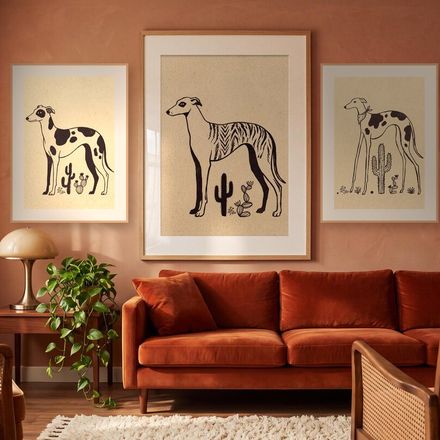 All three whippet prints framed together on a terracotta wall